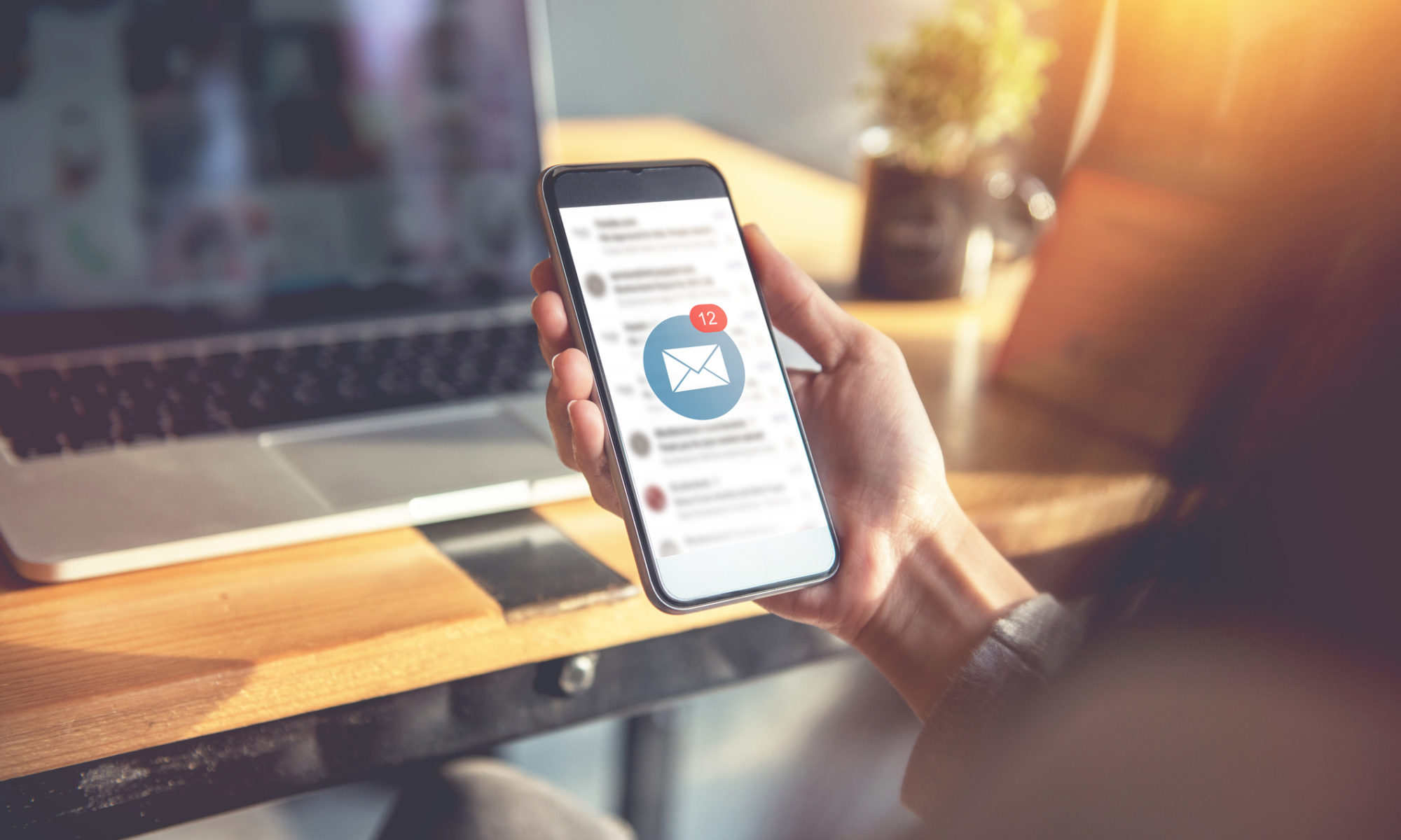 Close up of a person's hand holding a mobile phone as they check their emails