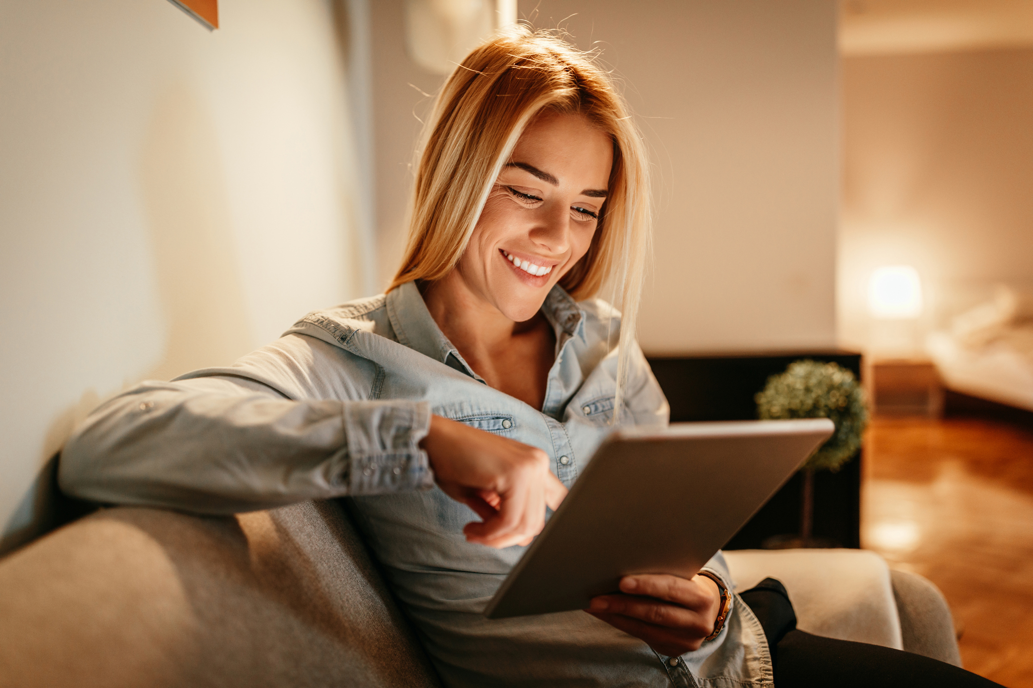 Attractive young woman holding a tablet at home reading up on permissions to run a business from home
