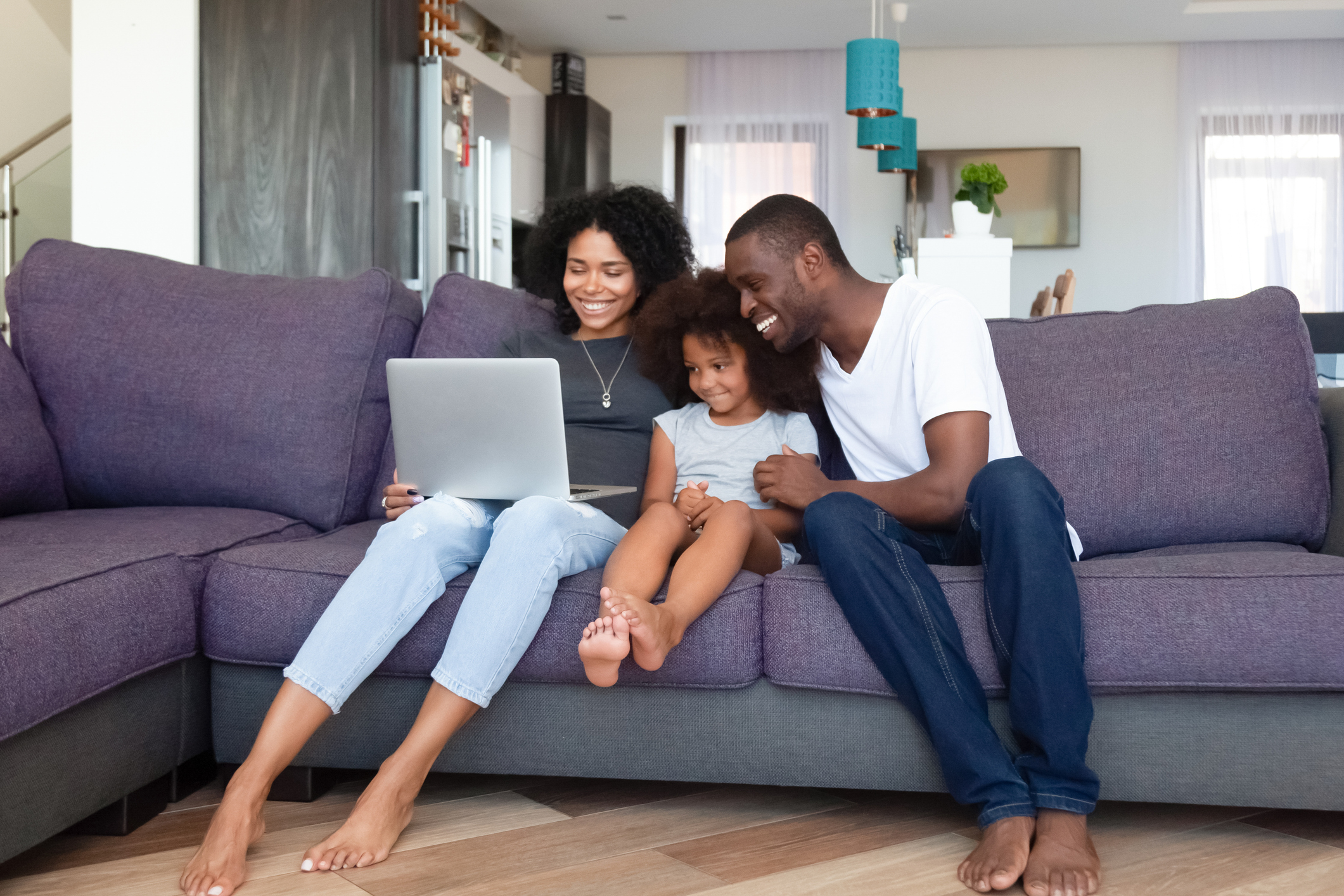 Happy African American family with daughter using laptop at home, shopping online and reading how online shopping websites work