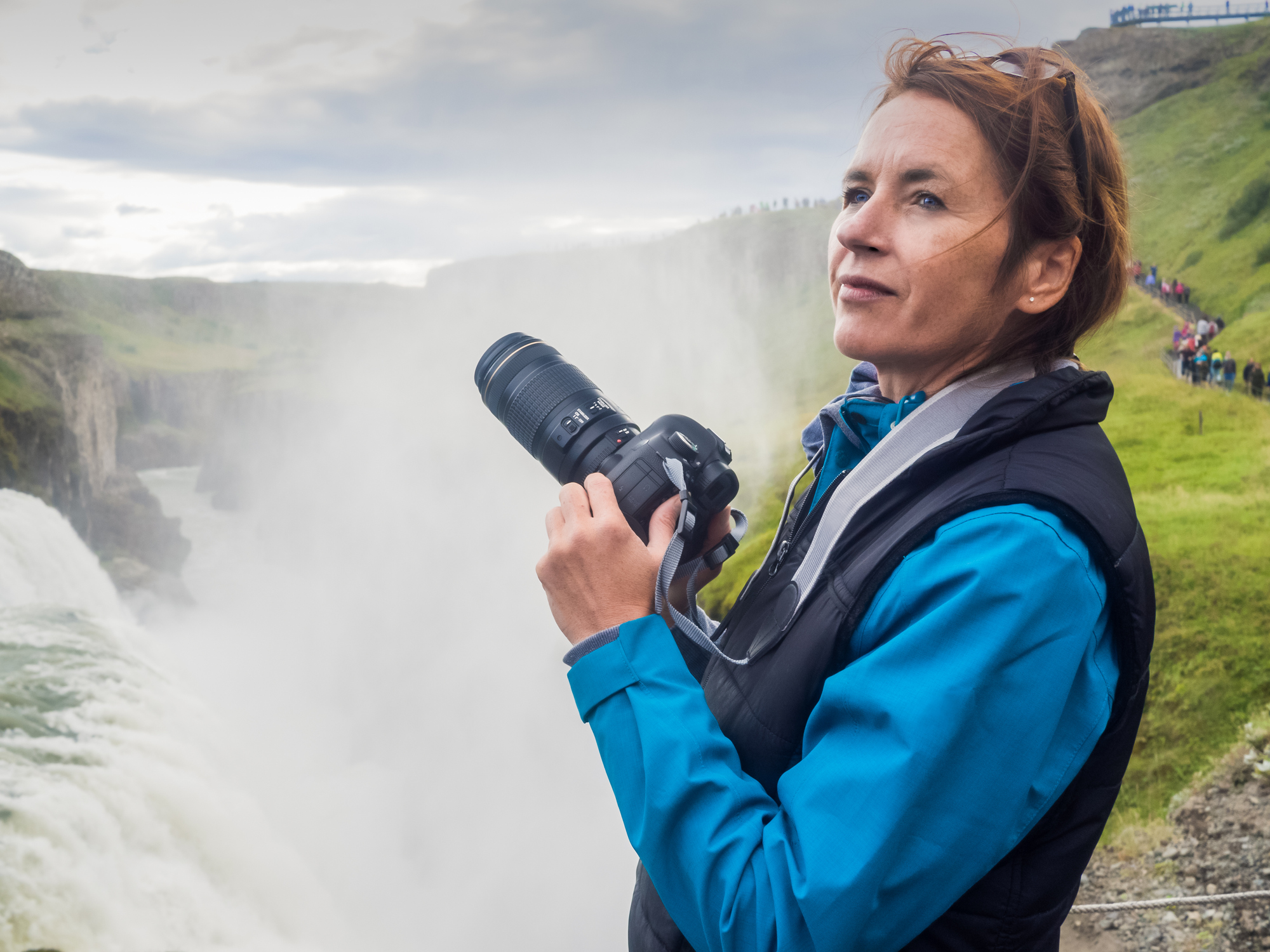 Female photographer in front of waterfall - Iceland thinking of the best photography website designs