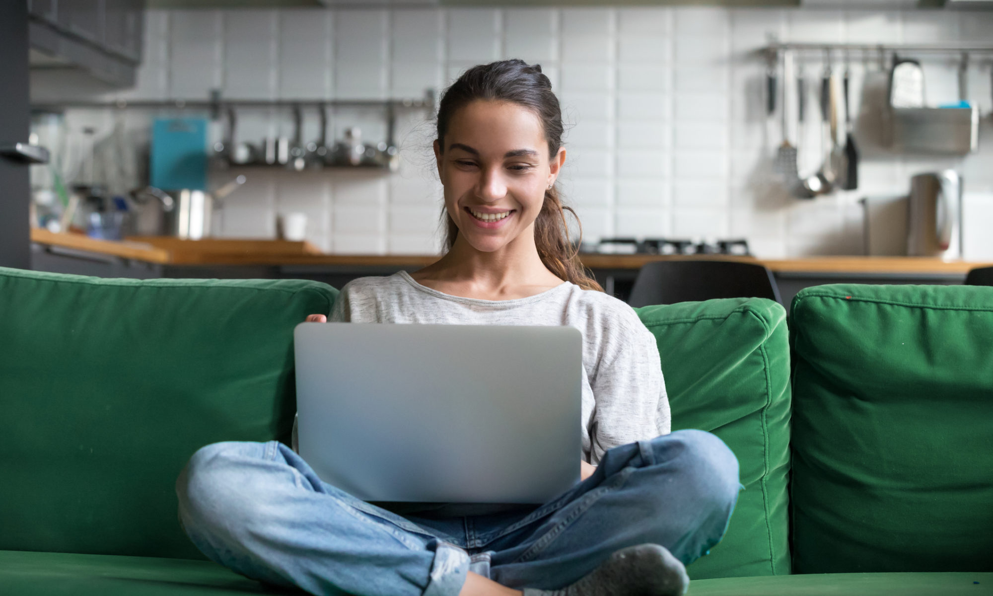 Happy smiling woman sitting on sofa, couch and using laptop to create an online store for free