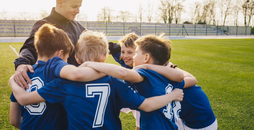 Group Of Children In Soccer Team Celebrating With Coach