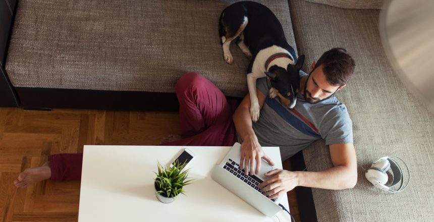 Male working on laptop from his home and hanging out with his dog pet finding out how much programming knowledge is needed to create my own website