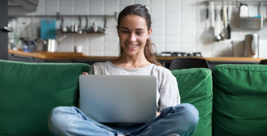 Happy smiling woman sitting on sofa, couch and using laptop to create an online store for free